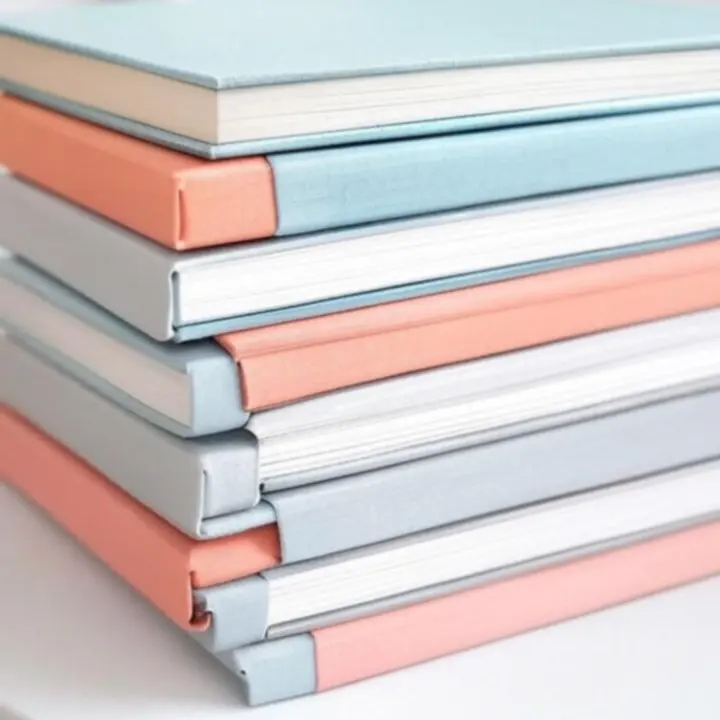 Pasztell színű jegyzetfüzetek egymásra helyezve, modern irodai hangulatban.